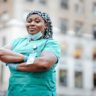 a nurse with her arms crossed smiling in the street