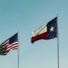 Texas flag flying next to the U.S. flag